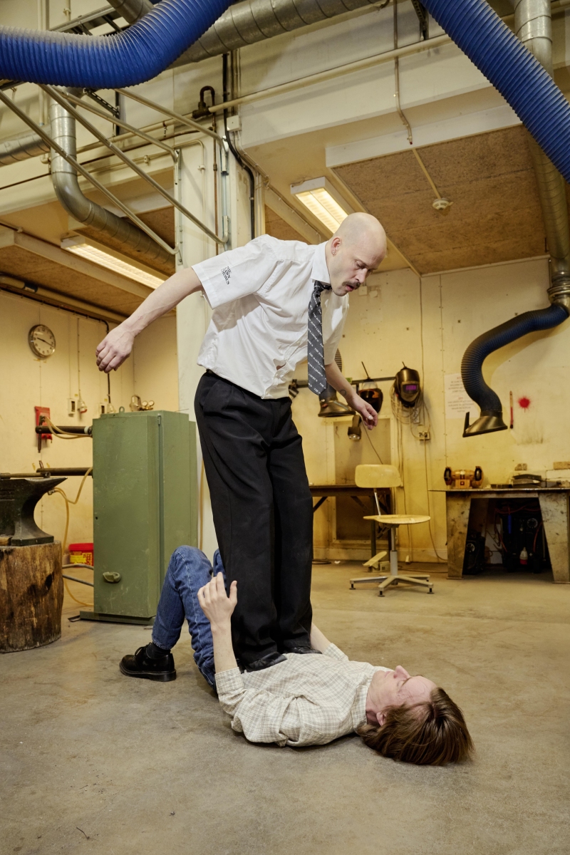 Pontus standing on Robert inside a metal workshop